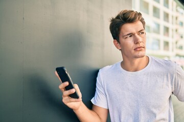 Young caucasian man with serious expression using smartphone at the city.