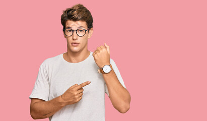 Handsome caucasian man wearing casual clothes and glasses in hurry pointing to watch time,...