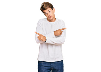 Handsome caucasian man wearing casual white sweater pointing to both sides with fingers, different direction disagree