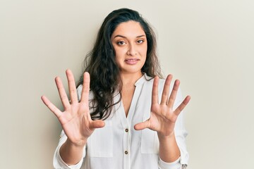 Beautiful middle eastern woman wearing casual clothes afraid and terrified with fear expression stop gesture with hands, shouting in shock. panic concept.