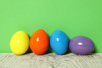 Easter eggs on white wooden table against green background