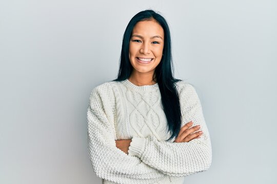Beautiful hispanic woman wearing casual winter sweater over white background happy face smiling with crossed arms looking at the camera. positive person.