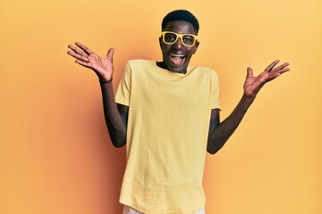 Young african american man wearing casual clothes and glasses celebrating crazy and amazed for success with arms raised and open eyes screaming excited. winner concept