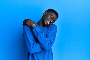 Young african american man wearing casual clothes hugging oneself happy and positive, smiling confident. self love and self care