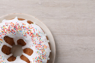 Glazed Easter cake with sprinkles on white wooden table, top view. Space for text
