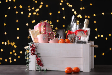Fototapeta na wymiar Wooden crate with Christmas gift set on grey table against festive lights