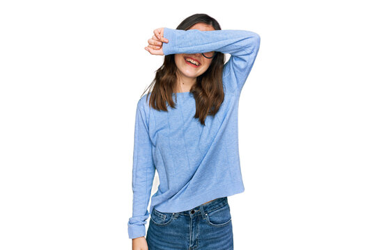 Young beautiful woman wearing casual clothes and glasses covering eyes with arm smiling cheerful and funny. blind concept.