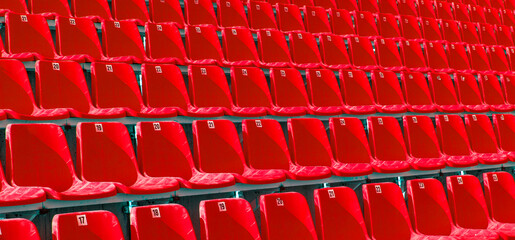 Folded red plastic chairs on a temporary tribune.