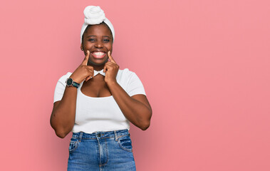 Young african woman with turban wearing hair turban over isolated background smiling with open mouth, fingers pointing and forcing cheerful smile