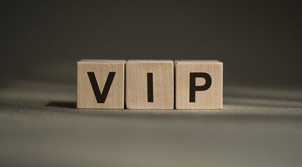 A wooden blocks with the word VIP written on it on a gray background.