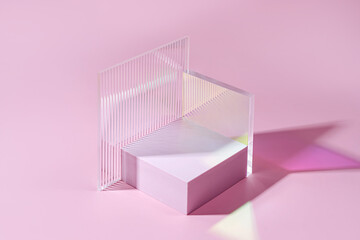Geometric shapes podium for product display. Monochrome platform  with gloss acrylic sheets on pink...