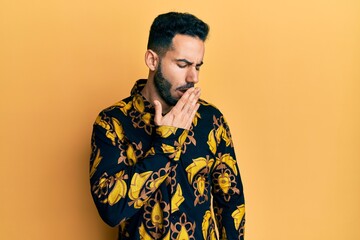 Young hispanic man wearing casual shirt bored yawning tired covering mouth with hand. restless and sleepiness.