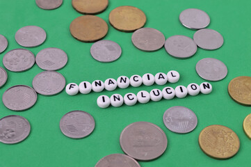Bunch of coins and alphabet beads with text FINANCIAL INCLUSION.