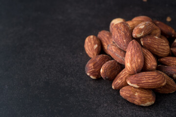 Pile of salted and roasted almond on dark background