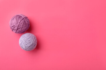 Soft colorful woolen yarns on pink background, flat lay. Space for text