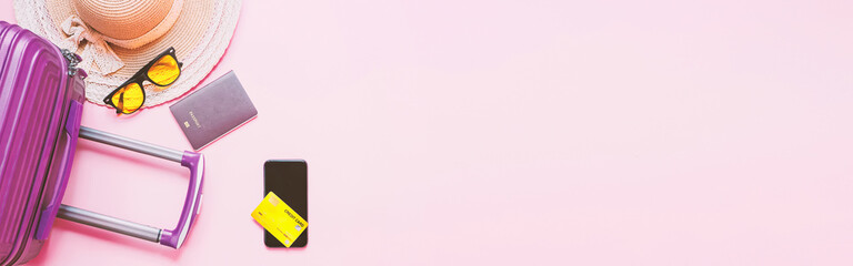 summer travel concept from credit card and suitcase with summer collection on pink background. web banner size.