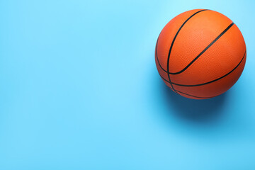 Fototapeta premium Orange ball on light blue background, top view with space for text. Basketball equipment