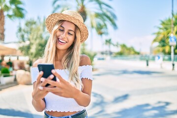 Young blonde tourist girl smiling happy using smartphone at the city.