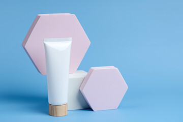 Cream tube mockup  with geometric forms on blue background. Background for branding and packaging presentation. Natural skincare beauty product concept.