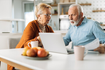 Angry mature couple arguing about their home finances at home