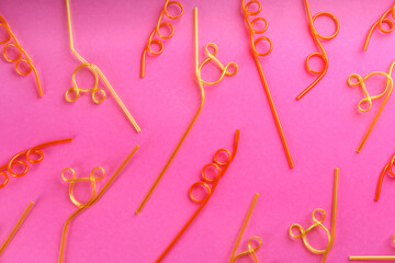 Colorful plastic drinking straws on pink background, flat lay