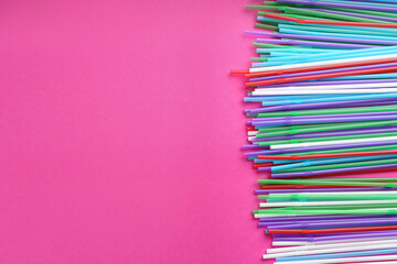 Fototapeta premium Colorful plastic drinking straws on pink background, flat lay. Space for text