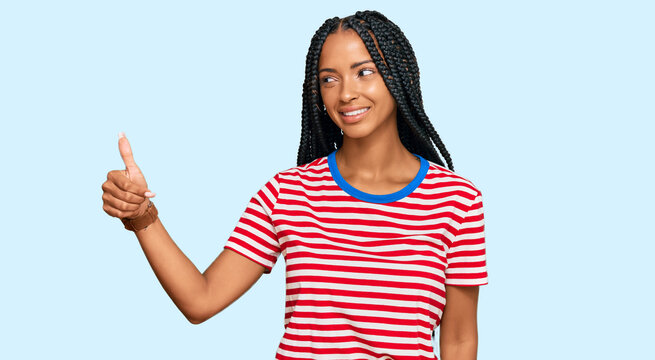 Beautiful hispanic woman wearing casual clothes looking proud, smiling doing thumbs up gesture to the side