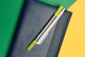 notepad with markers and pens on yellow green background and office supplies codespace