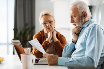 Fototapeta premium Old couple going through their finances together at home