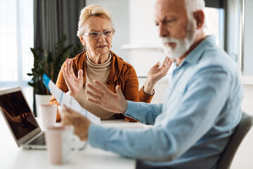 Obraz premium Frustrated senior couple arguing about their home finances at home