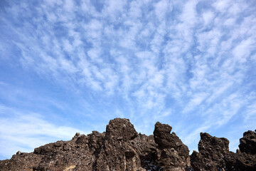 Fototapeta premium 冬の平沢峠、しし岩のある岩場を下から見上げた風景 青空と雲 長野県 南牧村