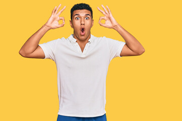 Fototapeta premium Young arab man wearing casual clothes looking surprised and shocked doing ok approval symbol with fingers. crazy expression