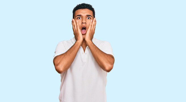 Young arab man wearing casual clothes afraid and shocked, surprise and amazed expression with hands on face