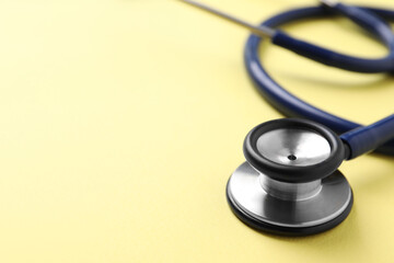 Stethoscope on yellow background, closeup. Space for text