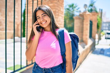 Young latin student girl smiling happy talking on the smartphone at university campus.