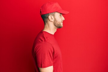 Young caucasian man wearing delivery uniform and cap looking to side, relax profile pose with natural face with confident smile.