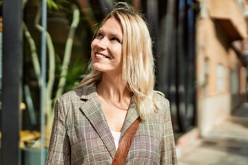 Young blonde businesswoman smiling happy standing at the city.