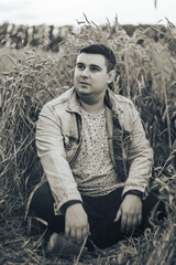 A young man in a field with green wheat