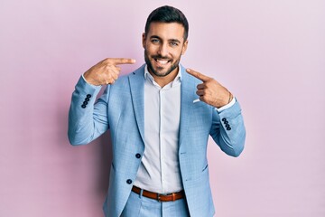 Young hispanic businessman wearing business jacket smiling cheerful showing and pointing with fingers teeth and mouth. dental health concept.