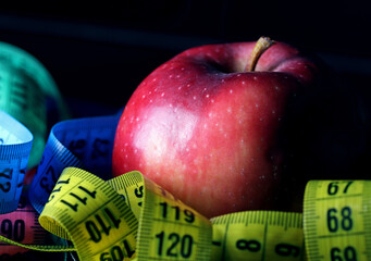 apple and measuring tape on black background