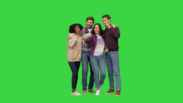 Four friends, two girls and two boys, taking a selfie, posing, smiling, looking at the camera on a Green Screen, Chroma Key.