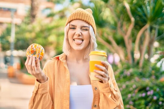 Young blonde girl smiling happy having breakfast at the park.