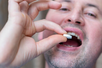 Extreme closeup man face taking white pill, mouth view swallowing pills, illness. man take medicine,open mouth and bring medicine to mouth. toned. selected focus