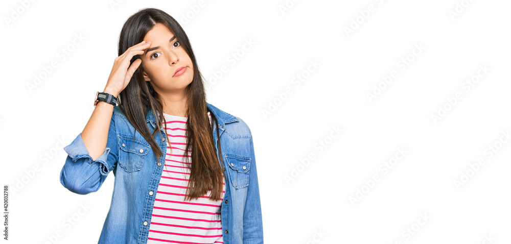 Wall mural Young brunette woman wearing casual clothes worried and stressed about a problem with hand on forehead, nervous and anxious for crisis