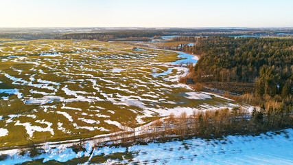 Season change. March rural landscape. Winter crops and plowed field panorama.