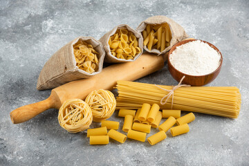 Pastas in rustic basket with rolling pin and a wooden cup of flour around