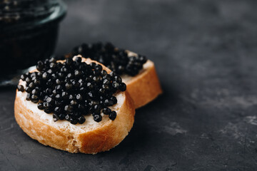 Black caviar sandwiches with butter on dark background