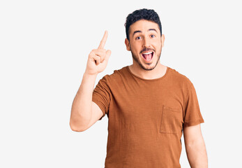 Naklejka premium Young hispanic man wearing casual clothes pointing finger up with successful idea. exited and happy. number one.