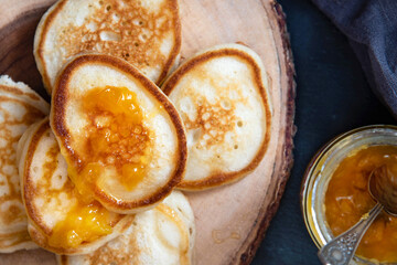 Pancakes with apricot jam on a wood board background.