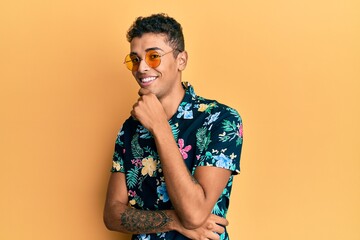 Young handsome african american man wearing summer style smiling looking confident at the camera with crossed arms and hand on chin. thinking positive.